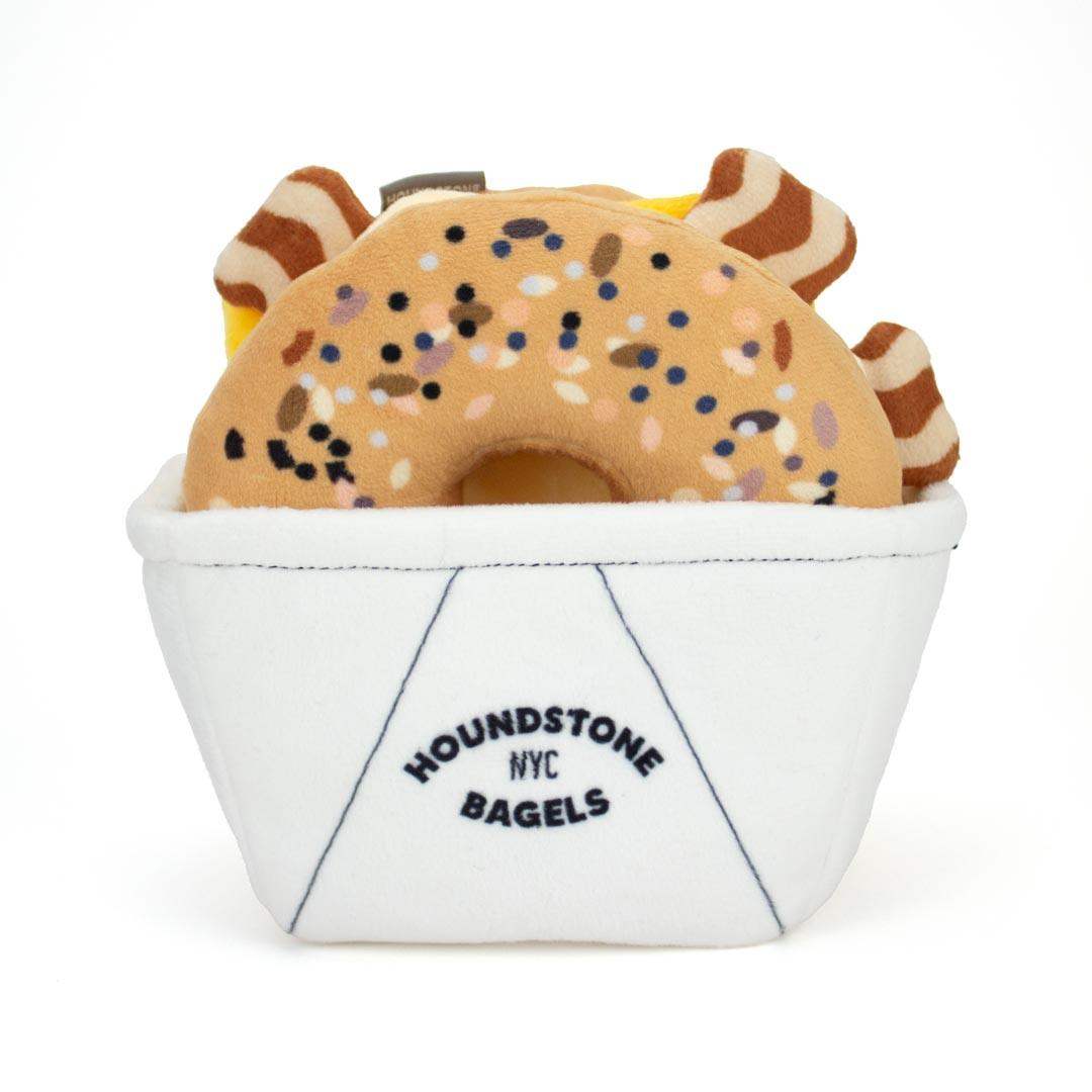 Interactive Dog toys shaped like a bagel with sprinkles in a white basket labeled 'Houndstone NYC Bagels' on a white background
