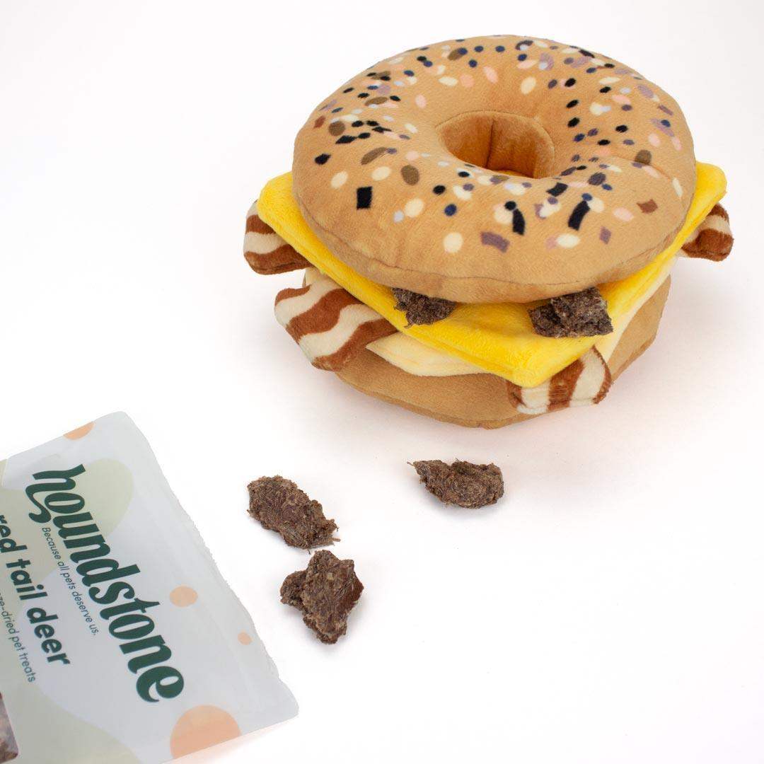 interactive Dog toy shaped like a bagel with cheese and bacon, branded 'houndstone' with low fat dog treats tucked in the bagel