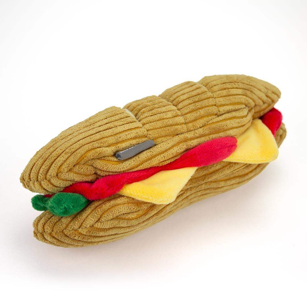Plush interactive dog toy shaped like a hot dog with mustard, ketchup, and relish on a white background