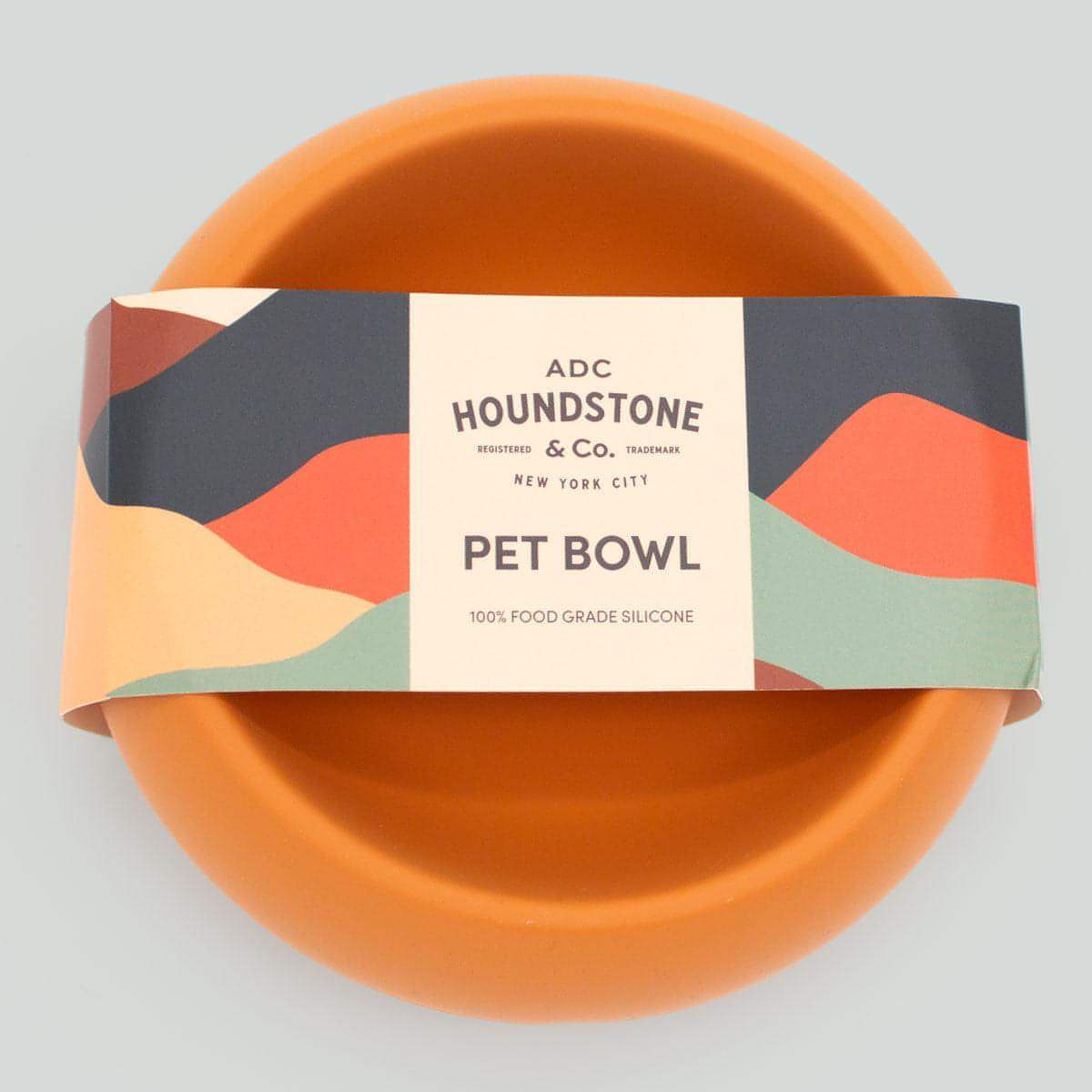 Orange dog bowl with a colorful Houndstone label on a gray background